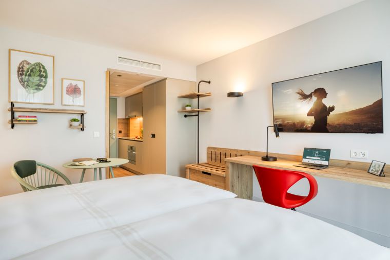 Studio mit einem Doppelbett, einem Fernseher mit Chromecast und einem Schreibtischbereich