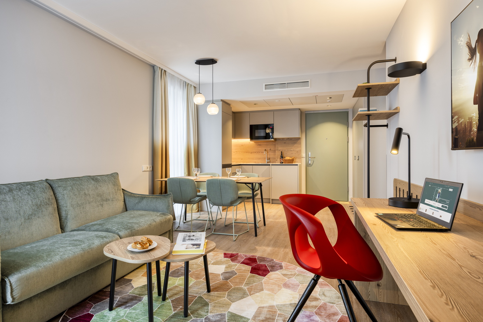 Wohnzimmer einer 2-Zimmer-Wohnung Executive mit Schlafsofa, Schreibtisch, Essbereich und voll ausgestatteter Küche