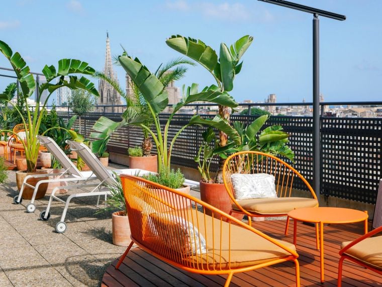 Terraza con tumbonas, sofás y sillas de mimbre con vistas panorámicas de Barcelona, apart hotel Barcelona