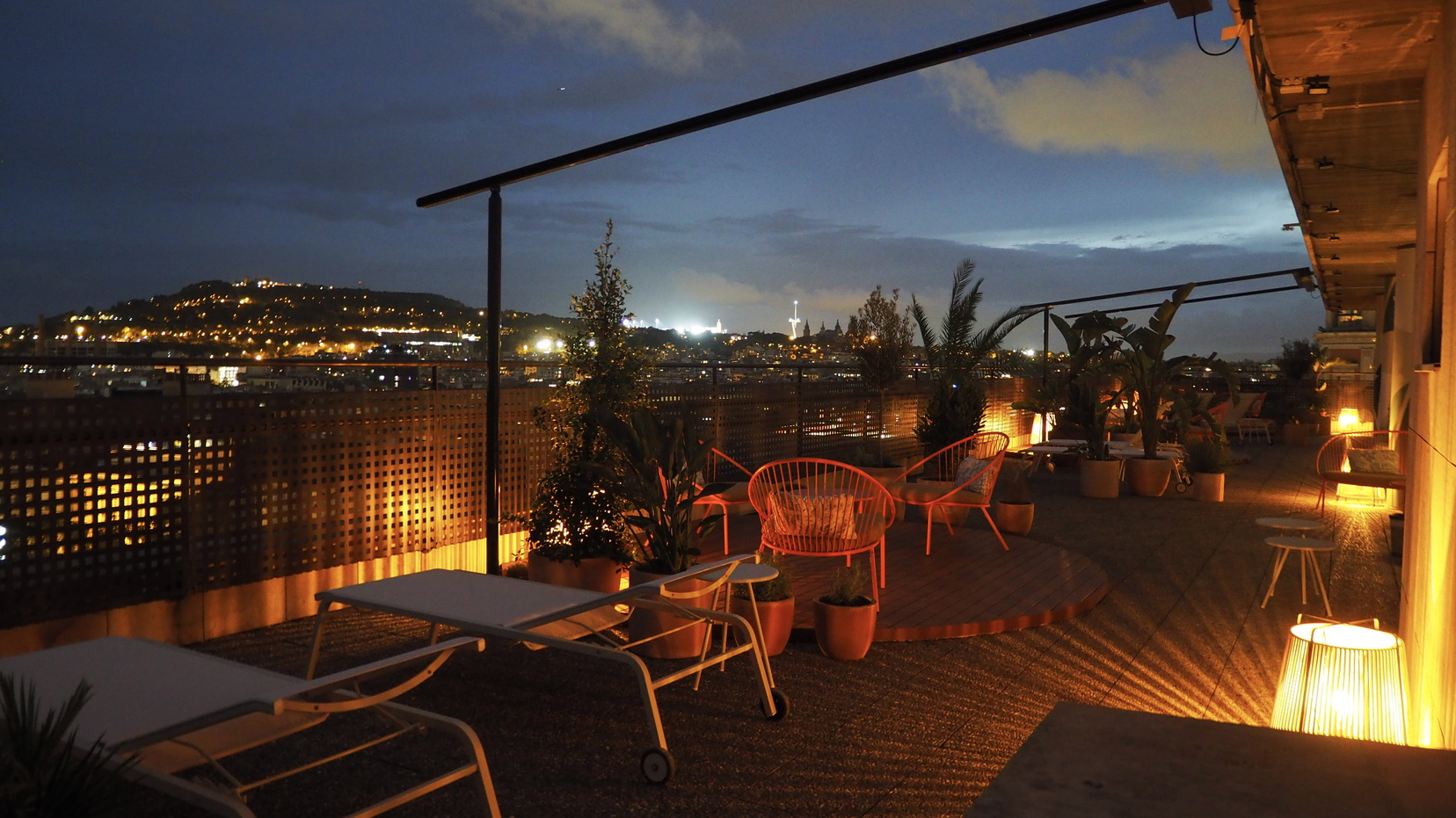 Terraza con tumbonas, sofás y sillas de mimbre con vistas panorámicas de Barcelona, apart hotel Barcelona