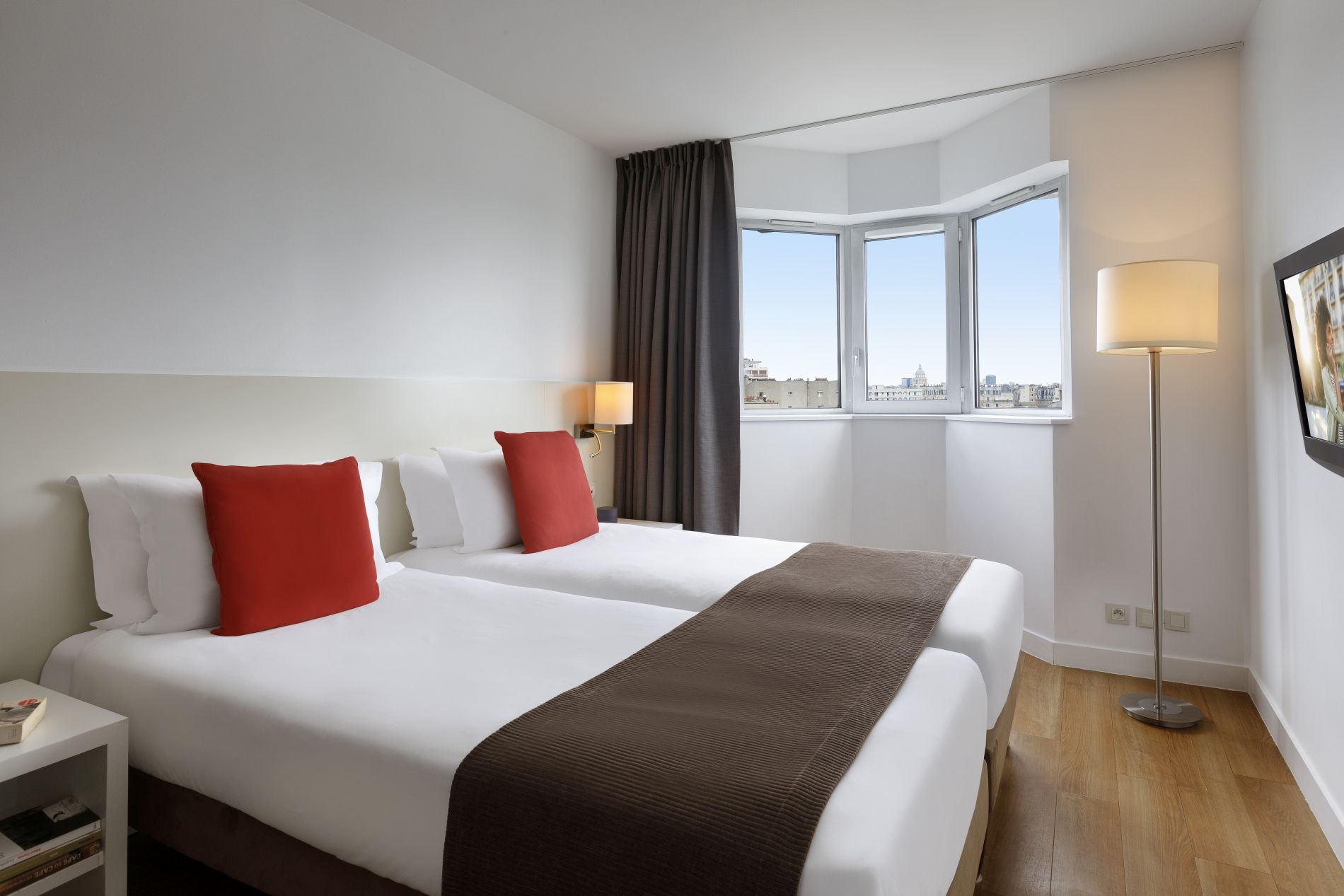 Bedroom of a 1-Bedroom Apartment equipped with two single beds and a television, apart hotel Paris 14